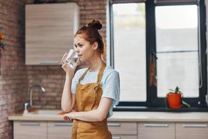 woman in a brown apron glass of water kitchen interior Lifestyle photo