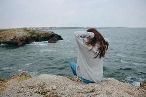 beautiful woman seated on the coast sweater landscape unaltered photo