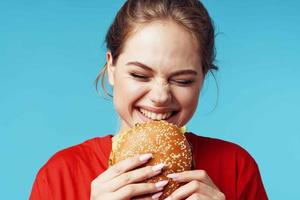 cheerful woman in red t-shirt hamburger in hands fast food blue background photo