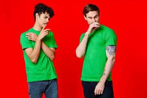Cheerful friends in green t-shirts gesturing with hands emotions photo