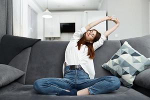 woman sitting on sofa with bent legs comfort in apartment photo