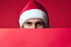 handsome man in a santa hat holding a banner holiday red background photo