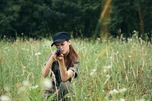 militar mujer un mujer arrodillado abajo toma objetivo con un arma Fresco aire foto