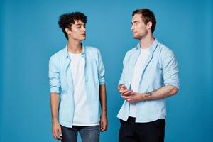 guys in identical shirts and a t-shirt on a blue background friends gesticulate with their hands photo