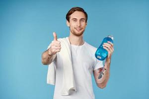 sporty man showing thumb up water bottle towel on shoulder cropped view blue background photo