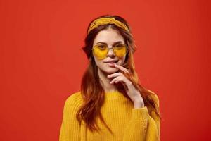 woman in yellow sweater hippie accessories retro style red background photo