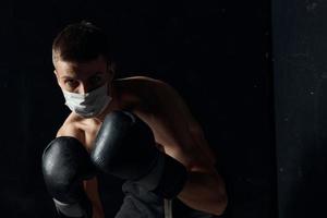 retrato de un Boxer en un médico máscara y negro guantes en un aislado antecedentes Copiar espacio foto