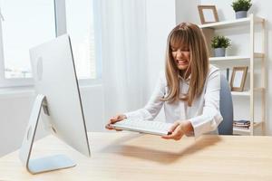 Irritated blonde businesswoman screaming to keyboard Raging after computer software crash error at workplace in modern office. Angry evil director work online in financial corporation. Copy space photo