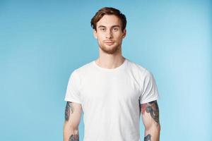 man with tattoos on his arms white t-shirt cropped view blue background photo
