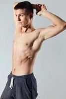 handsome athlete with inflated torso holds his hands behind his head bodybuilder cropped view photo