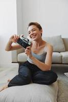 Happy smile woman holding an old camera and taking pictures of herself as a weekend photographer in home clothes with a short haircut hair without filters on a white background, free copy space photo