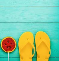 Summer accessories. Flip flops, sunglasses, towel, red cap and oranges on blue wooden background. copy space. photo