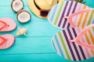 chanclas, gafas de sol y conchas de mar sobre fondo de madera azul. copie el espacio y los accesorios de moda de verano. foto