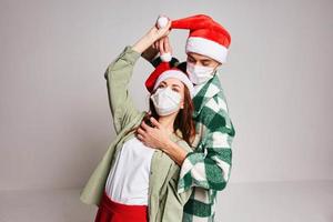 Man and woman embrace fun and holiday medical New Year masks photo