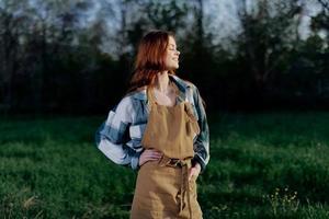 Woman farm worker in apron relaxing in nature and watching the sunset after a day of work on the farm photo