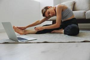 Woman exercising at home by video workout online, meditation and stretching, mental health photo