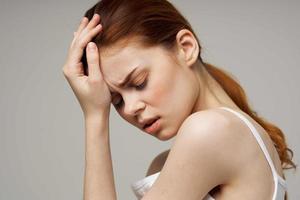 woman in white t-shirt holding head migraine disorder isolated background photo