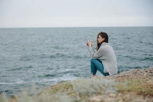 bonito mujer suéteres nublado mar admirativo naturaleza relajación concepto foto