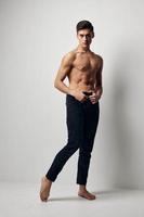 Guy in jeans and a naked torso room light background muscles sporty appearance photo