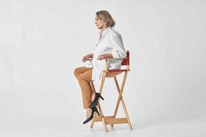 aged woman in white shirt sits on a chair red lips isolated background photo