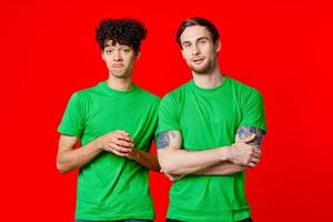 two men in green t-shirts are standing next to friendship red background photo