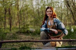 A girl bird farm worker smiles and is happy pouring food into the chicken feeder in the fresh air sitting on the green grass photo