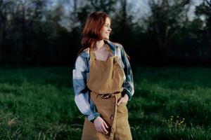 Woman farm worker in apron relaxing in nature and watching the sunset after a day of work on the farm photo