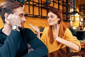 a woman gestures with her hands and tells something to a handsome man with a watch on his hand photo