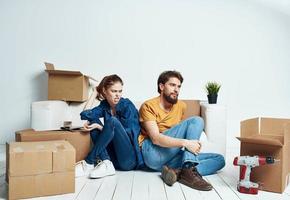 A man and a woman are sitting on the floor with open boxes and tools for repair photo