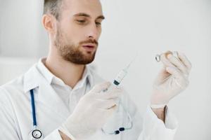 médico con vacuna ampolla en manos y jeringuilla inyección médico guantes estetoscopio codicioso foto