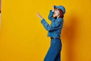 positivo joven mujer elegante mezclilla ropa posando amarillo antecedentes inalterado foto