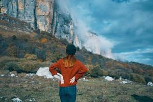 viajero en un suéter en el otoño montañas al aire libre paisaje azul cielo alto rocas modelo foto