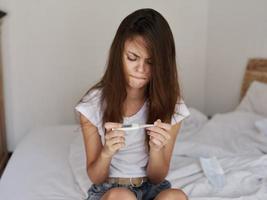 woman sitting on bed and looking at thermometer dissatisfaction photo