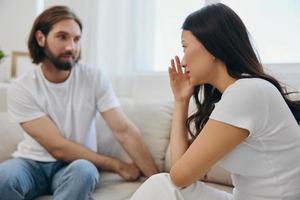 An Asian woman is sad and crying with her male friend at home. Stress and misunderstanding in a relationship between two people and supporting each other's mental and emotional well-being photo