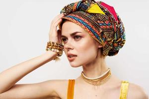 pretty woman holding her head decoration multicolored turban fashion light background photo