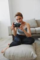 Happy smile woman holding an old camera and taking pictures of herself as a weekend photographer in home clothes with a short haircut hair without filters on a white background, free copy space photo