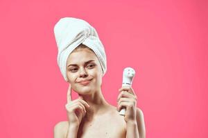 woman with towel on head naked shoulders skin care cosmetology pink background photo