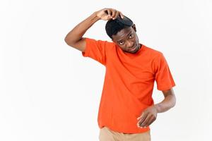 un hombre de africano apariencia en un naranja camiseta peinada su pelo foto