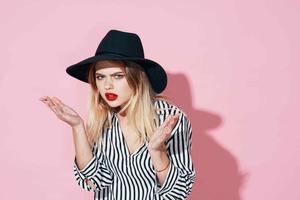 atractivo mujer en negro sombrero y a rayas camisa brillante maquillaje rosado antecedentes foto