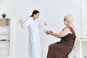 an elderly woman at a doctor's appointment a large syringe hospital photo