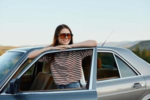 A young woman driver looks out of the car at the autumn landscape and smiles satisfactorily photo