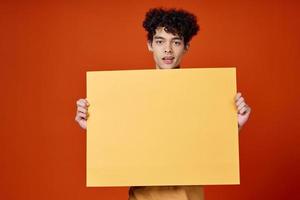 emotional man with curly hair yellow poster in hands photo