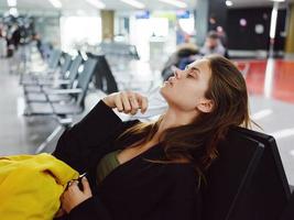 woman with closed eyes sitting at the airport waiting for flight luggage photo