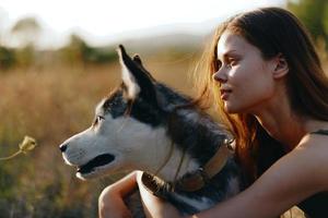 mujer sentado en un campo con un perro tejonero perro sonriente mientras gasto hora en naturaleza con un amigo perro en otoño a puesta de sol foto