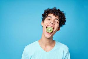 handsome man with kiwi curly hair in his mouth cropped view in blue background photo