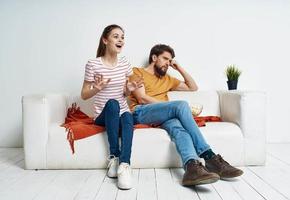 A woman in a striped T-shirt and a man on the couch watching the TV in a bright room photo