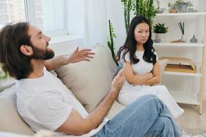 A man looks at the phone screen during an argument with his girlfriend. The angry and hurt woman looks in his direction and is sad. Family discord at home, phone addiction photo