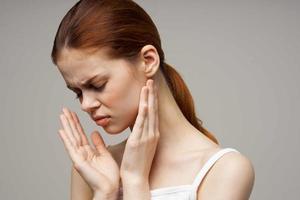 disgruntled woman holding on to face pain in teeth light background photo