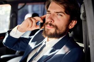 negocio hombre con un barba hablando en el teléfono en un coche viaje foto