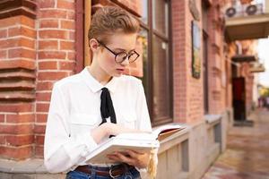 student with glasses walking around the city with a book education photo